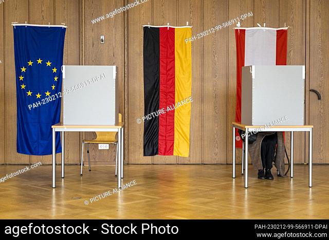 12 February 2023, Berlín;: A woman chooses her vote in a polling booth, where the rerun elections for the regional parliament and the councils of the twelve...