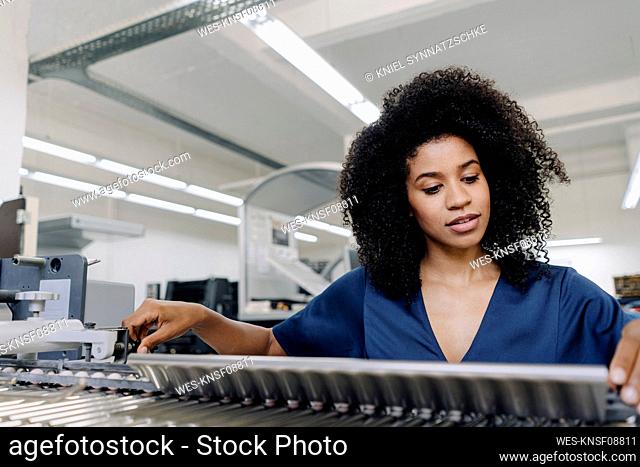 Afro businesswoman adjusting machinery at printing industry