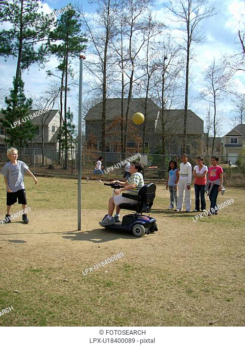 A boy, who uses a wheelchair, plays tether ball with some friends at recess