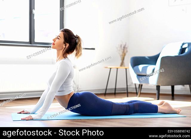 young woman doing cobra pose at yoga studio