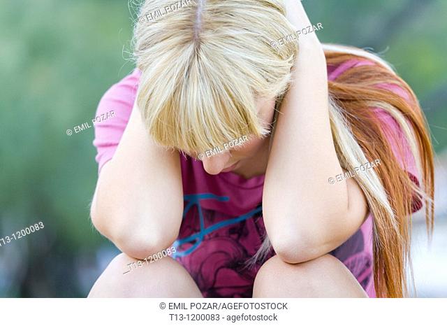Holding her head between hands depressed young woman
