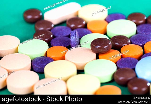 Multi-colored pills on a green background of various packs, a bunch of drugs on paper, medical treatment help