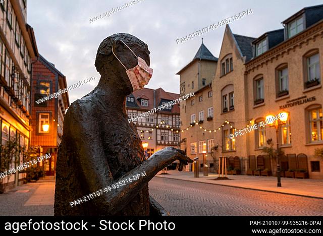 26 December 2020, Saxony-Anhalt, Wernigerode: Someone has put a mask on a bronze figure in the historic old town. Normally