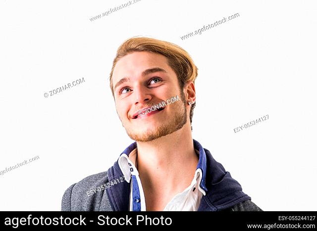 Attractive young man thinking, looking up with hand on his chin, isolated on white background, with doubtful expression