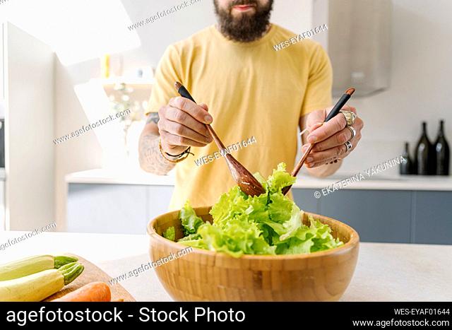 Mid adult man mixing vegetables with spoon in kitchen