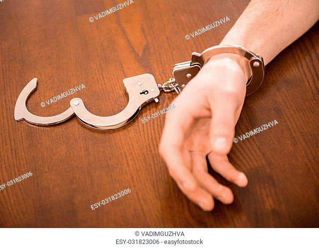 Close-up of man hand with handcuffs on the table