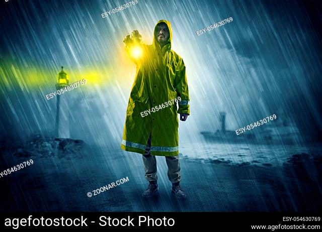 Man at the coast coming in raincoat with glowing lantern concept