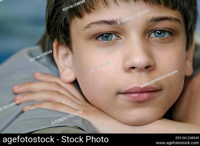 Close up portrait of a five years old young Caucasian boy with a bright blue eyes impishly looking straight into the camera and expressing positive emotions on...