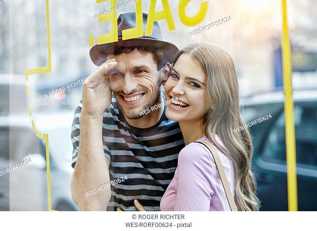Young couple looking through window of a coffee shop