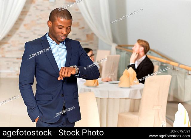 Hadsome Asian businessman in business suit looking at his watch in order not to be late for next business meeting