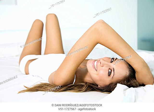Portrait of a pretty blonde woman smiling at camera in bed