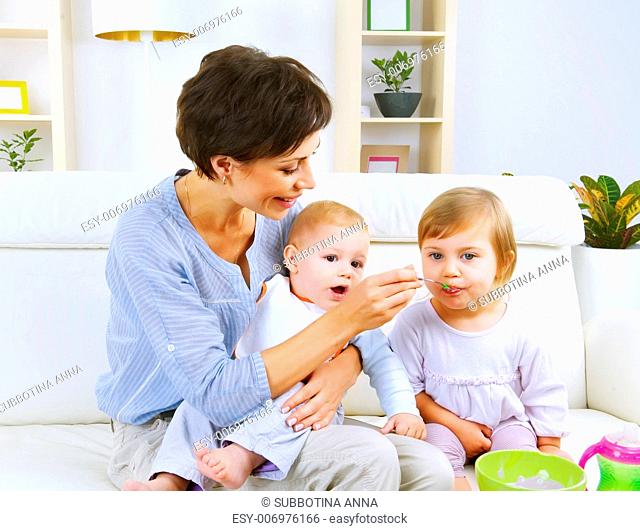 Mother feeding baby food to babies