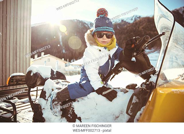 Italy, Val Venosta, Slingia, boy with sunglasses sitting on a snowmobile