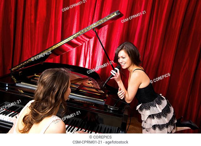 Two women singing a duet with a concert piano