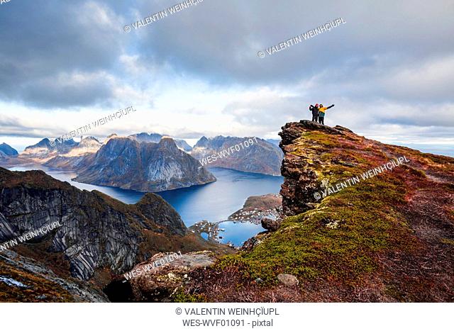 Norway, Lofoten Islands, Reine, men with raised arms standing on Reinebringen