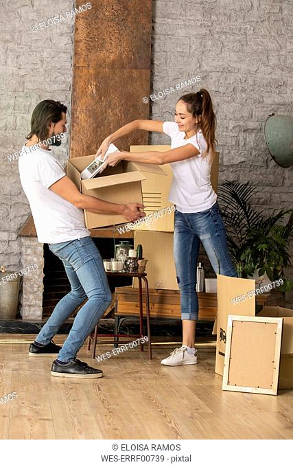 Couple packing cardboard box in new home