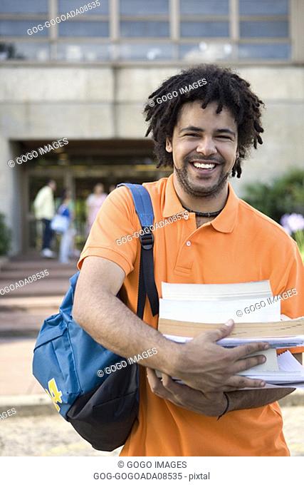 Male student carrying stack of textbooks