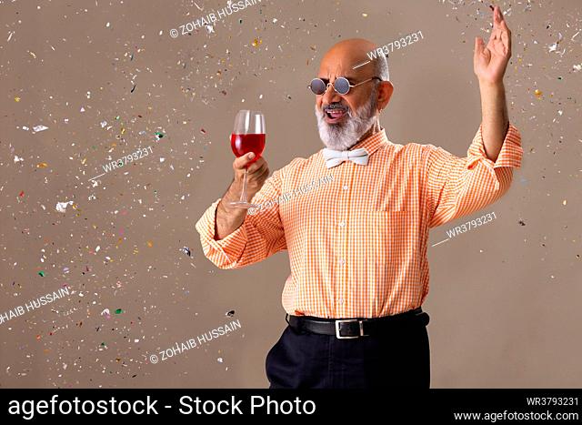 Senior man cheering with a glass of red wine