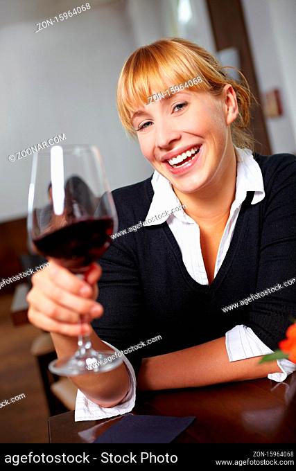 Junge Frau im Restaurant prostet mit Rotwein