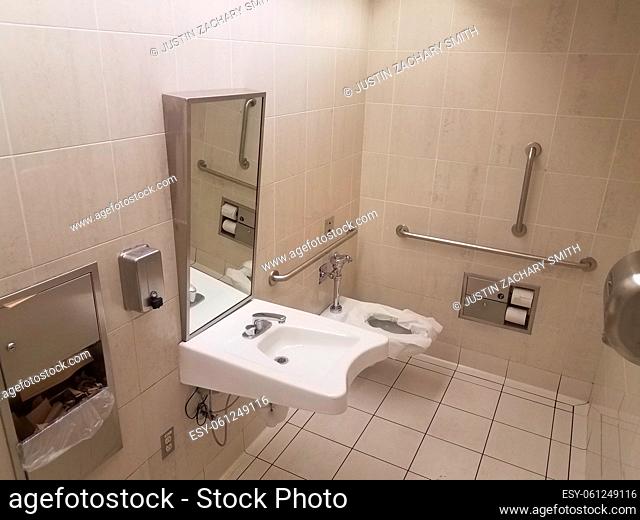 bathroom or restroom toilet with paper and metal railings and sink