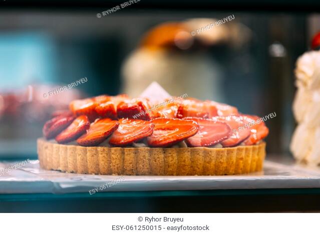 pie with strawberries, assortment baked pastry in bakery. Various Different Types Of Sweet Cakes In Pastry Shop Glass Display