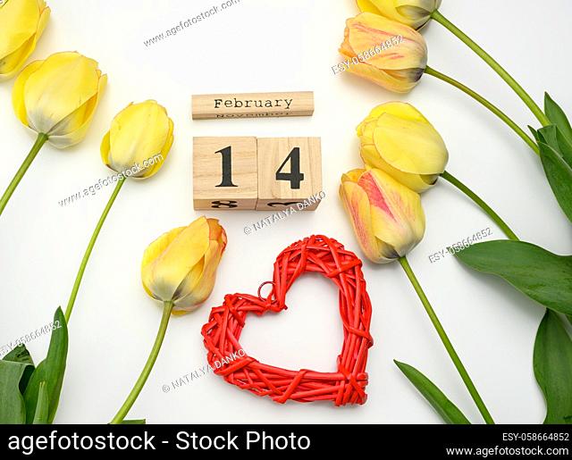 yellow tulips, wooden calendar with date 14 February and red heart on white background, top view