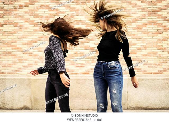 Two women tossing her hair
