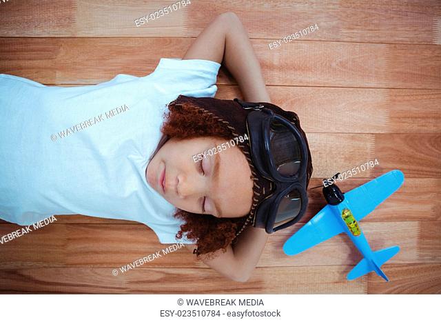Smiling girl sleeping on the floor wearing aviator glasses and hat