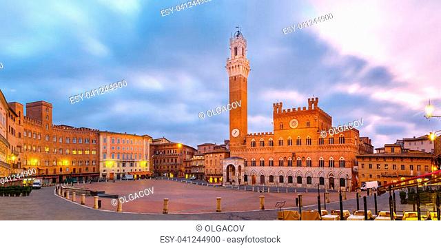 Mangia Tower or Torre del Mangia towering above of the Palazzo Pubblico on Piazza del Campo in medieval city of Siena at beautiful sunrise, Tuscany, Italy