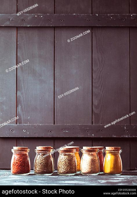 Various grinded spices in vintage glass bottles, place for text