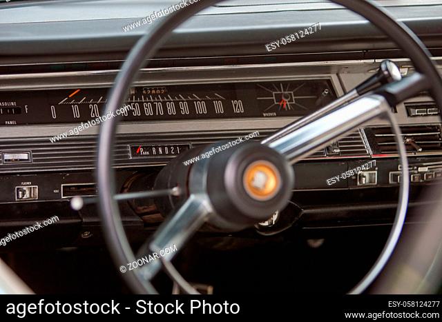 Close up detail of the front interior of a 60's vintage red Chrysler 300 showing the dashboard and steering wheel
