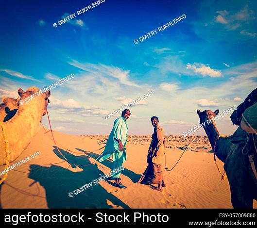 Vintage retro hipster style travel image of Vintage retro hipster style travel image of Rajasthan travel background - two indian cameleers (camel drivers) with...