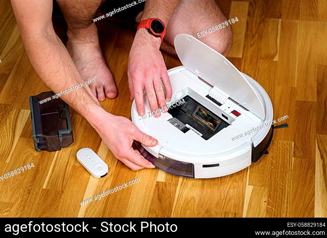Housework and technology concept. Maintenance and service of robot vacuum cleaner. Cleaning, repair, replacement of parts