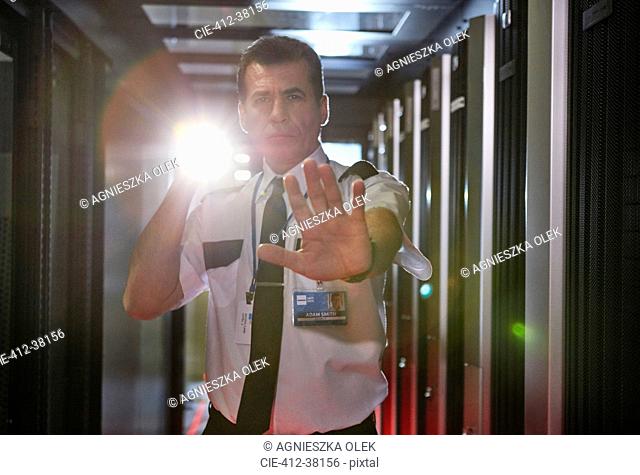 Portrait male security guard with flashlight gesturing stop in server room