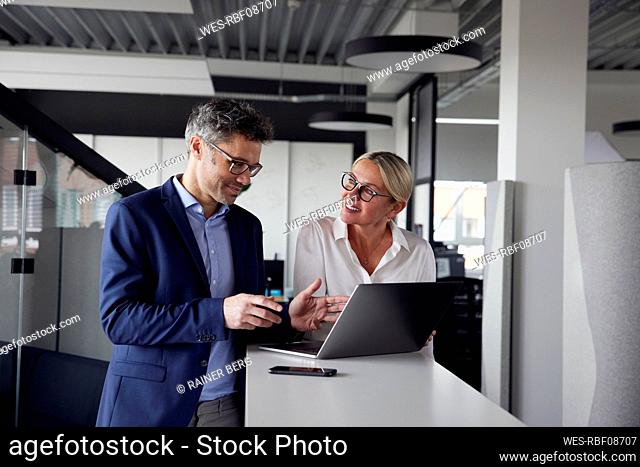 Business colleagues sharing ideas working on laptop in office