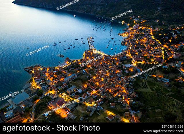 Aerial view of seaside town of Komiza on Vis island, Croatia in Dalmatia from drone at night with street lights on. Tourist destination in the Mediterranean Sea