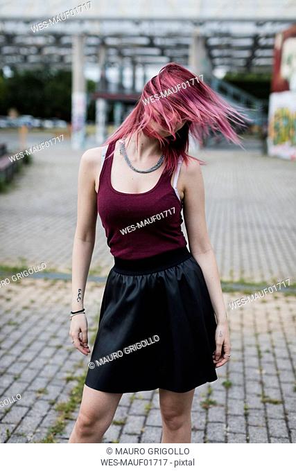 Young woman shaking her dyed hair outdoors