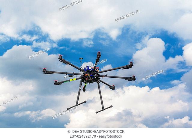 Multicopter in flight on sky and clouds background