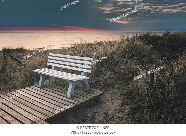 Germany, RANTUM/SYLT, 10.04.2016, Sitzbank in den Dünen mit Blick über die Nordsee vor Sylt, Abendstimmung. Am Horizont sind die Windräder vom Windpark...