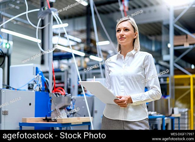 Businesswoman holding digital tablet in factory