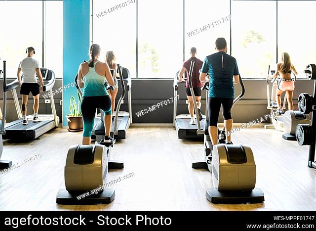 Men and women on exercise machines at gym