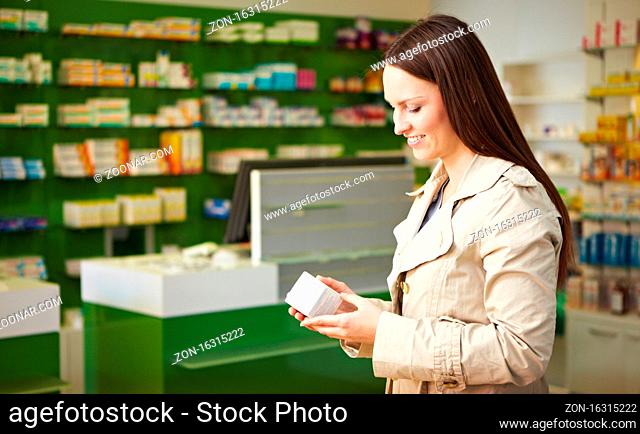 Frau in Apotheke liest Packung eines Medikaments