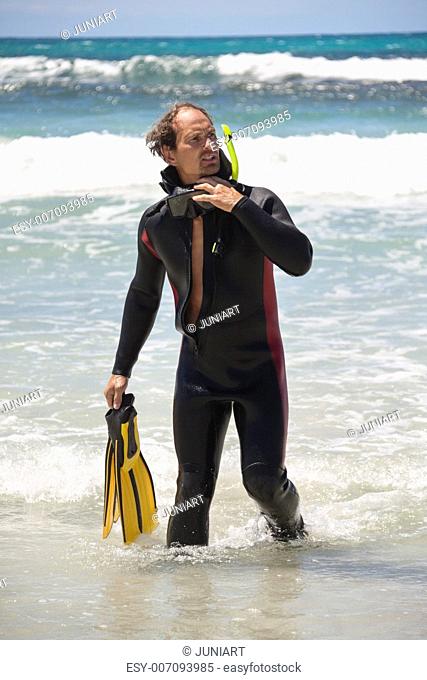 male diver with diving suit snorkel mask fins on the beach in Summer