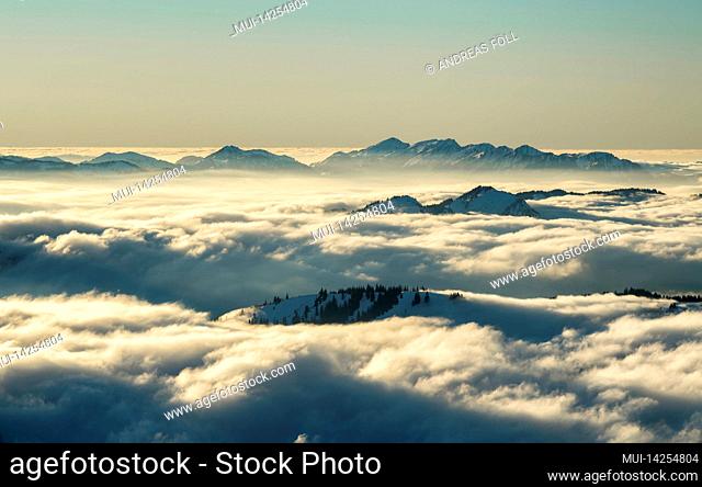 Alpine mountain landscape on an atmospheric afternoon in winter. The Allgäu Alps with the Nagelfluhkette rise out of the blanket of high fog