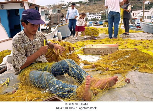 Fisherman using hands and feet to repair fishing net on Mykonos, Cyclades Islands, Greek Islands, Greece, Europe