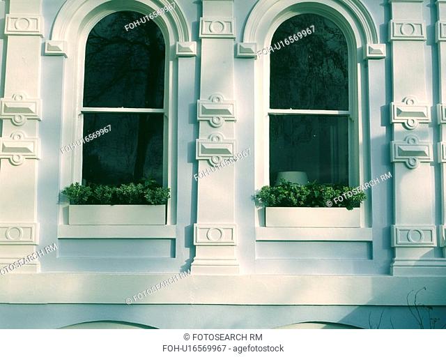 Close up of ornate plasterwork and arched sash windows with buxus in windowboxes