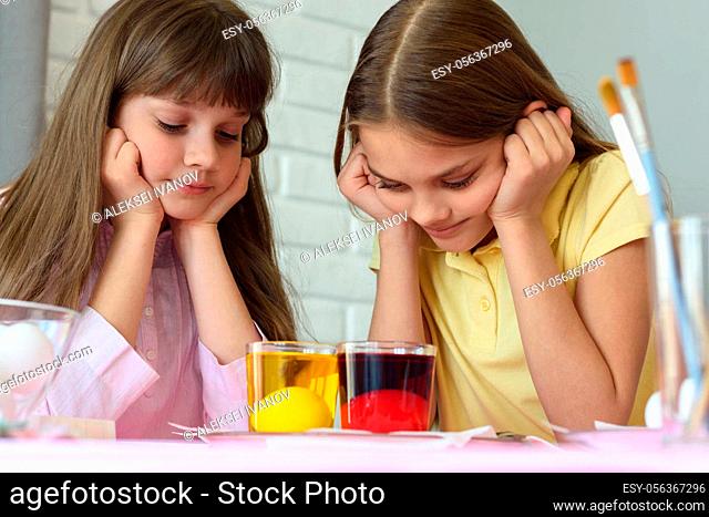 Children look in glasses with liquid dye while egg staining