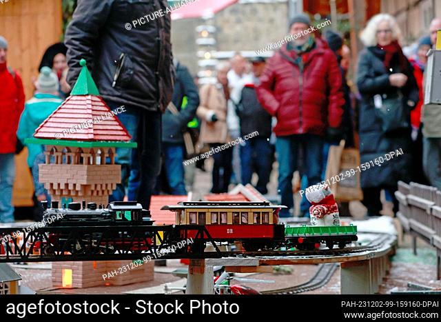 02 December 2023, Saxony-Anhalt, Quedlinburg: A model train runs at a small Christmas market in a courtyard in the Advent town of Quedlinburg