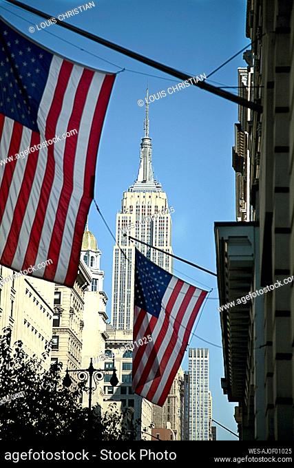 USA, New York, New York City, American flags hanging against Empire State Building
