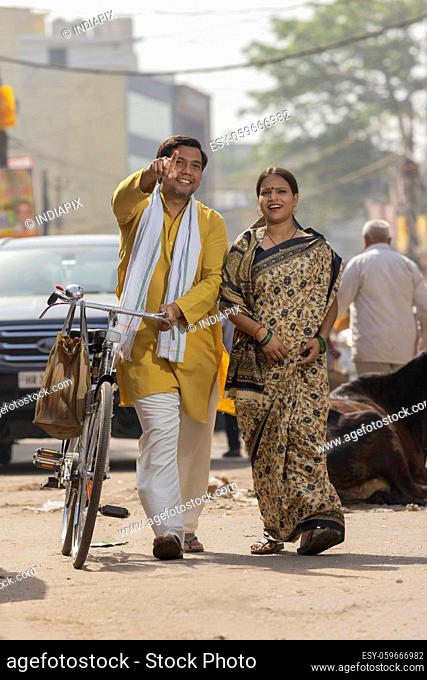 A RURAL HUSBAND POINTING AWAY HAPPILY WHILE WALKING WITH WIFE